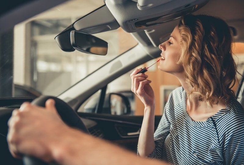 Una mujer que se maquilla en un coche